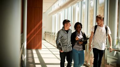 Deux étudiants et une étudiantes qui marchent dans un corridor