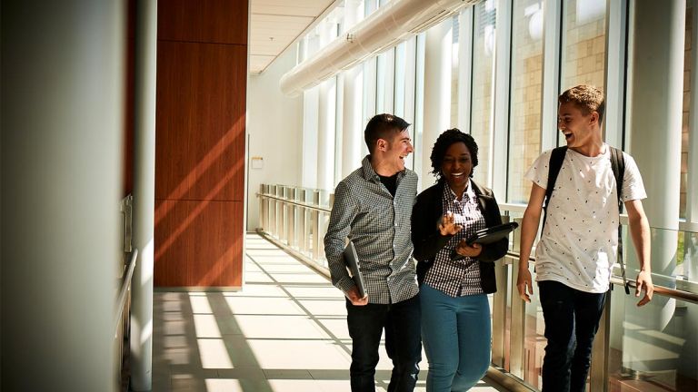 Deux étudiants et une étudiantes qui marchent dans un corridor